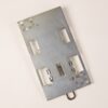 Metal mounting plate for an electronics module with several rectangular cutouts and a central spring-loaded contact.