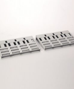 Two gray plastic panels with a grid of rectangular holes, laid on a white surface.