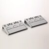Two gray plastic cable organizers lying on a white surface, each with multiple slots for guiding and bundling wires.