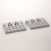 Two light gray perforated plastic panels with a grid of rectangular slots, resting on a white surface.