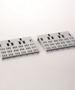 Two light gray perforated plastic panels with a grid of rectangular slots, resting on a white surface.