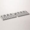 Two gray perforated plastic panels with a grid of small rectangular cutouts, laid angled on a white surface.