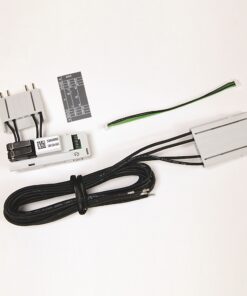 Electronic hardware kit laid out on a white surface: a gray module with a black connector, a second gray housing, a long coiled black cable, a small label card, and a green/black two‑conductor ribbon cable.