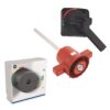 Group of electrical control components: a wall-mounted rotary switch, a red lockout device, and a white panel switch/control unit.