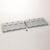 Two gray panels with ventilation slots and curved cutouts lie side by side on a white surface, with four small black screws between them.