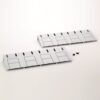 Two gray modular plastic panels with four raised rectangular sections and vertical vent slots, with screws nearby on a white surface.