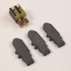 Three dark gray plastic electrical connector housings laid on a light surface, with a small gold-plated two-terminal plug nearby.