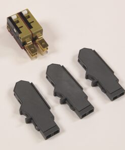 Three dark gray plastic electrical connector housings laid on a light surface, with a small gold-plated two-terminal plug nearby.