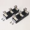 Six black electrical contactors with silver terminals and mounting screws laid on a light surface, plus loose screws nearby