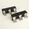 Eight black circuit breaker modules with silver terminal lugs arranged in two rows on a white surface