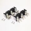 Eight black electrical relays with metal terminals arranged in two rows on a white background, plus screws nearby by the bottom edge