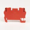 Red plastic electrical connector module with side clamps and a central circular recess, shown from the side.