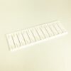 Row of white plastic binder combs mounted on a slim strip, laid on a pale surface, likely for binding documents.