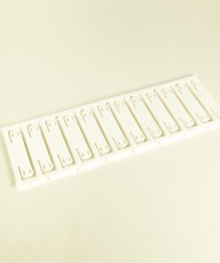 Row of white plastic binder combs mounted on a slim strip, laid on a pale surface, likely for binding documents.