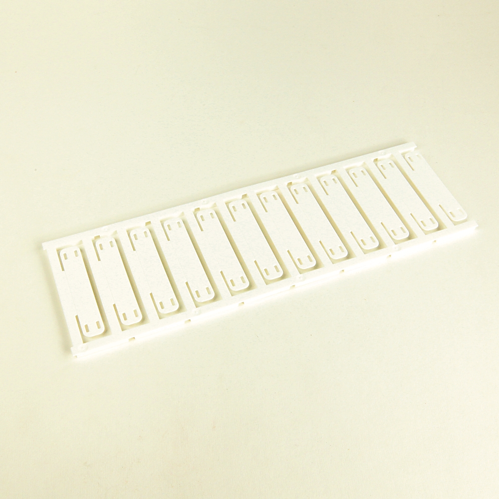 Row of white plastic binder combs mounted on a slim strip, laid on a pale surface, likely for binding documents.