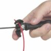 Close-up of a hand gripping a soldering iron with a metal tip and a red cord.