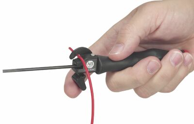 Close-up of a hand gripping a soldering iron with a metal tip and a red cord.